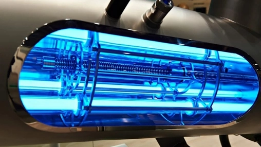 Close-up of a UV water treatment chamber glowing with intense blue light showing internal quartz tubes